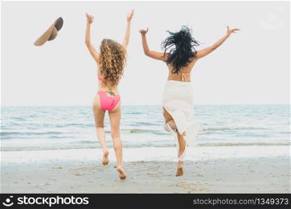 Happy women in bikinis jumping in the air together on tropical sand beach in summer vacation. Travel lifestyle.. Happy women jumping on sand beach in summer.