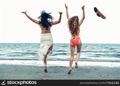 Happy women in bikinis jumping in the air together on tropical sand beach in summer vacation. Travel lifestyle.. Happy women jumping on sand beach in summer.