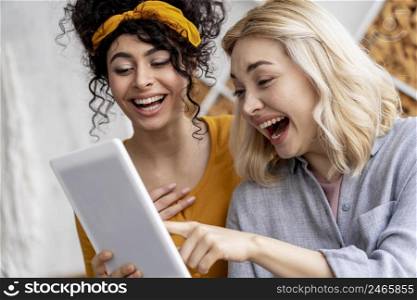 happy women laughing holding tablet