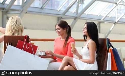 Happy women talking in cafe after shopping in mall