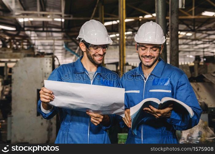 Happy Work. Factory Engineer with white safety helmet smile and relax talk during work on production in a factory. Industrial,Warehouse Heavy Mechanic, Engineering Concept.