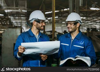 Happy Work. Smiling Factory Engineer or mechanical worker with white safety helmet checking on production in a factory. Industrial,Warehouse Heavy Mechanic, Engineering Concept.