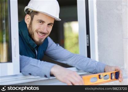 happy worker inspecting a window sill using a builders level