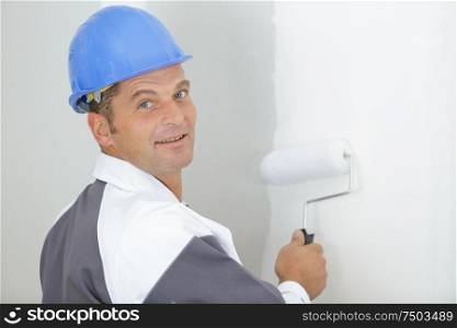 happy worker painting wall in room