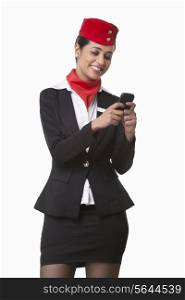 Happy young airhostess messaging on cell phone isolated over white background