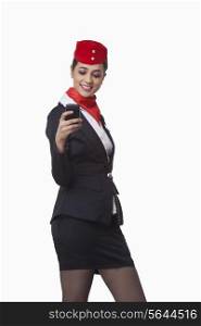 Happy young airhostess text messaging on cell phone isolated over white background