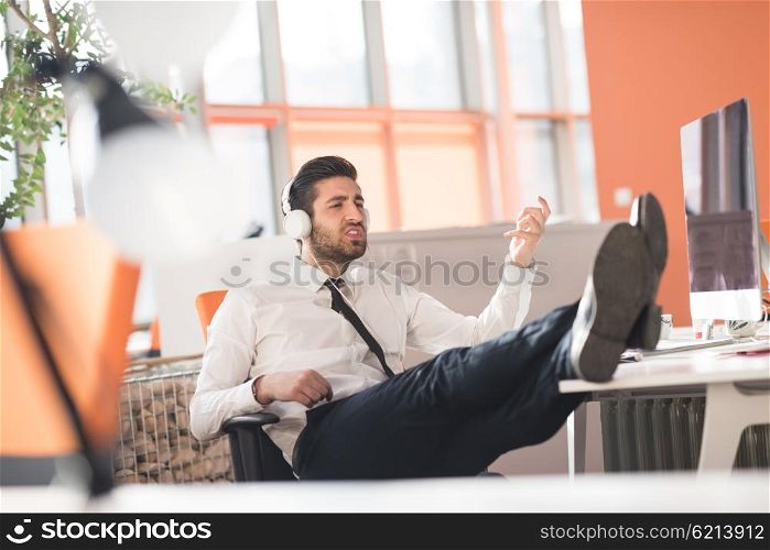 happy young arabian business man with beard listening music on headphones at modern startup office