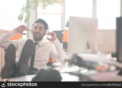 happy young arabian business man with beard listening music on headphones at modern startup office