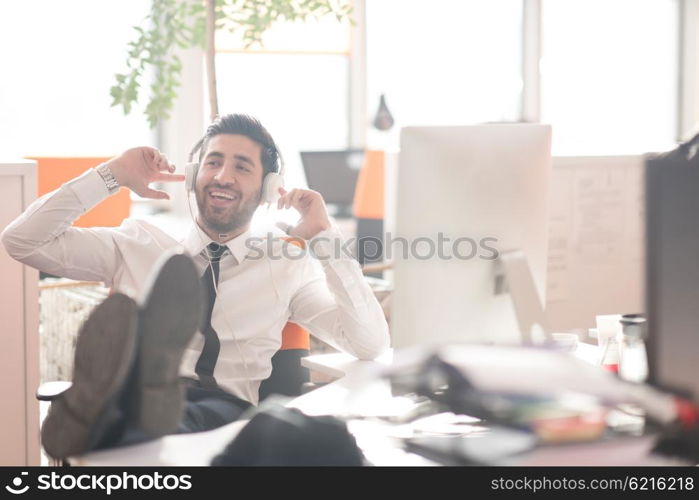 happy young arabian business man with beard listening music on headphones at modern startup office