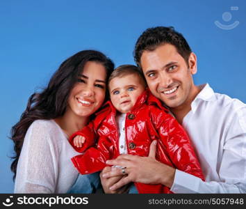 Happy young arabic family, blue sky background, cheerful parents with cute little child, spending time together, active and friendly lifestyle