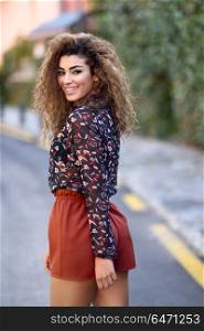 Happy young arabic woman with black curly hairstyle.. Happy young arabic woman with black curly hairstyle. Arab girl smiling in the street moving her hair.