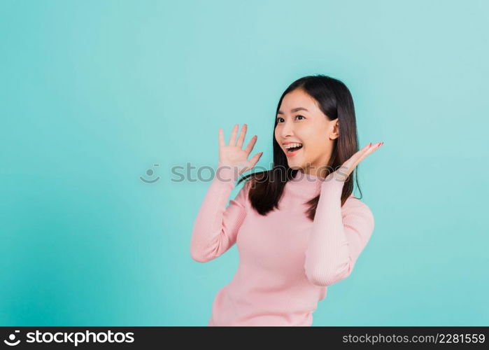 Happy young Asian beautiful woman smiling wear silicone orthodontic retainers on teeth surprised she is excited screaming and raise hand make gestures wow, studio shot isolated on blue background