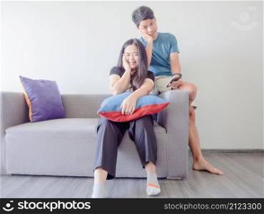 Happy young Asian couple in love relaxing on the sofa.