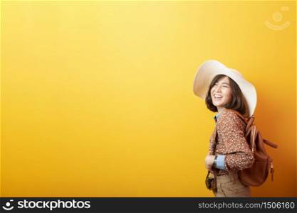 Happy Young Asian tourist woman on yellow background