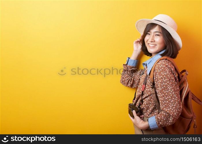 Happy Young Asian tourist woman on yellow background