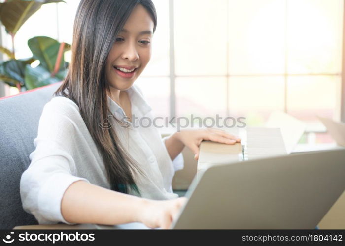 Happy young Asian woman entrepreneur, Smile for sales success after checking order from online shopping store in laptop at home office, Concept of merchant business online and eCommerce