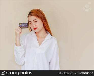 Happy young asian woman holding credit card in hand, showing confidence for making payment with feeling excited and amazed, isolated background.