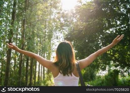 Happy young Asian woman traveler with backpack walking in forest. Hiker Asian woman with backpack walking on path in summer forest. Adventure backpacker travel people concept.