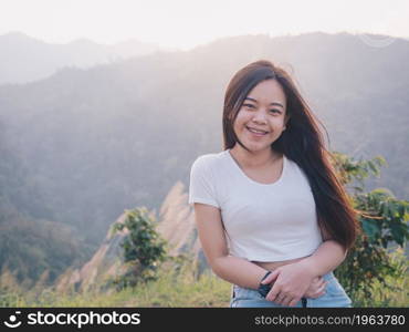 Happy young Asian woman traveler with mountain in evening sunset background.