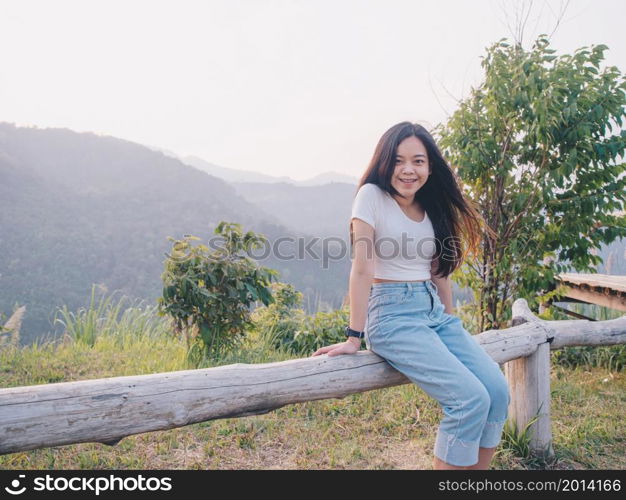 Happy young Asian woman traveler with mountain in evening sunset background.