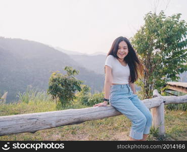 Happy young Asian woman traveler with mountain in evening sunset background.