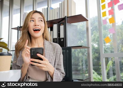 Happy young Asian women startup entrepreneur happy and excited smiling after getting message for success sign business contact, happy girl on workplace. Distance learning online education and work.