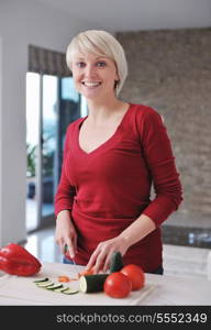 happy young beautiful blonde woman prepare food in the kitchen at home