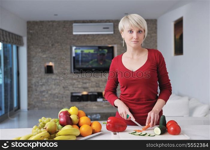 happy young beautiful blonde woman prepare food in the kitchen at home