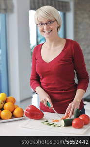 happy young beautiful blonde woman prepare food in the kitchen at home