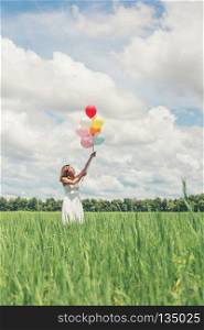 Happy young beautiful woman holding balloons in the grass field enjoy with fresh air.. Happy young beautiful woman holding balloons in the grass field 