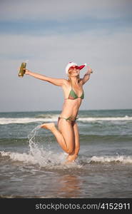 Happy young beautiful woman in christmas hat jumping on the waterfront