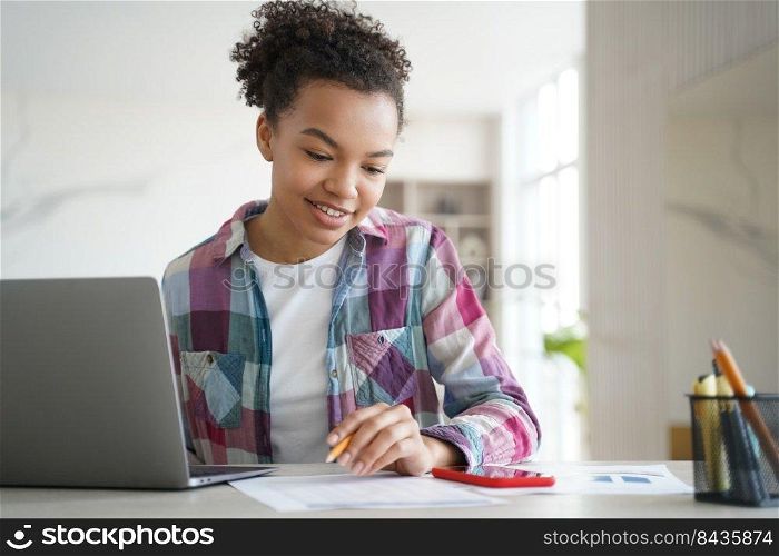 Happy young biracial girl student learning at laptop look at smartphone screen chatting in social network. Schoolgirl teenage distracted from school tasks, homework. Gadget addiction concept.. Biracial girl student learning at laptop look at smartphone, distracted from study. Gadget addiction