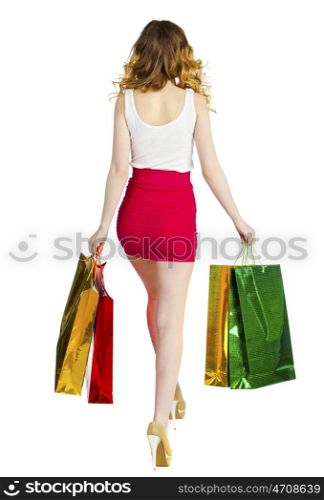 Happy young blonde girl with colorful shopping bags in red skirt posing on a white background