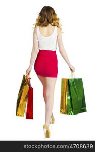 Happy young blonde girl with colorful shopping bags in red skirt posing on a white background