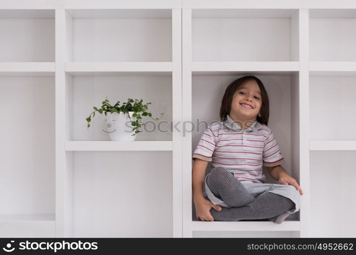 happy young boy having fun while posing on a shelf in a new modern home