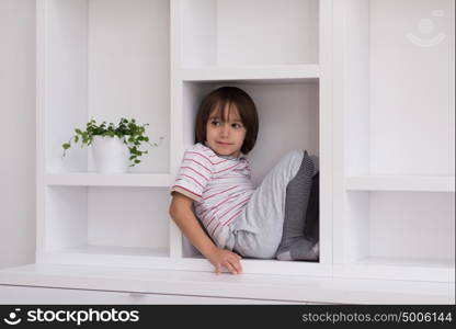 happy young boy having fun while posing on a shelf in a new modern home