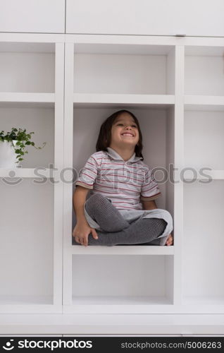 happy young boy having fun while posing on a shelf in a new modern home