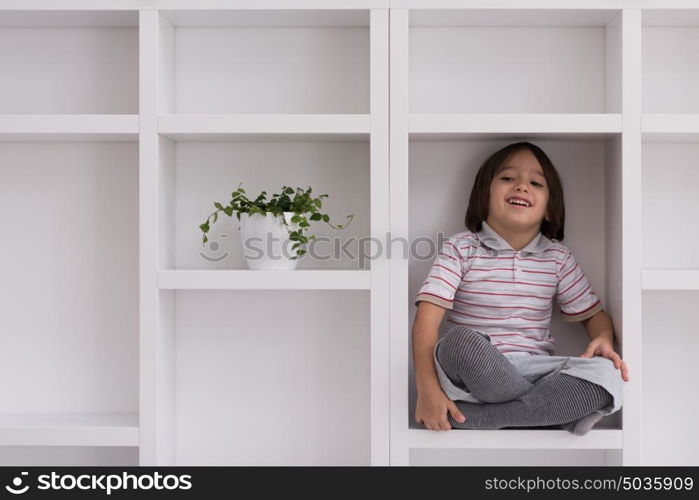 happy young boy having fun while posing on a shelf in a new modern home