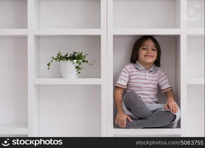 happy young boy having fun while posing on a shelf in a new modern home