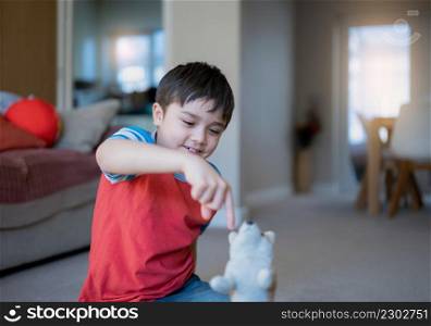 Happy young boy lying on floor playing with dog toy, Kid with smiling face playing alone at home on weekend, Positive Child relaxing at home in the morning