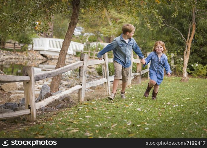 Happy Young Brother and Sister Running Together Outside.