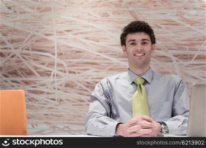 happy young business man working on laptop computer at his desk in modern startup office interior