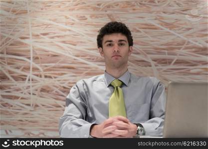 happy young business man working on laptop computer at his desk in modern startup office interior