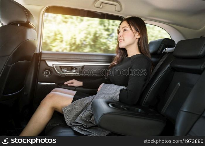 happy young business woman sitting at the back seat of car