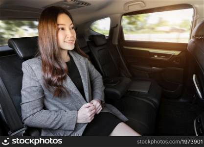happy young business woman sitting at the back seat of car