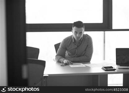 happy young businessman at his desk at work in modern startup business office interior
