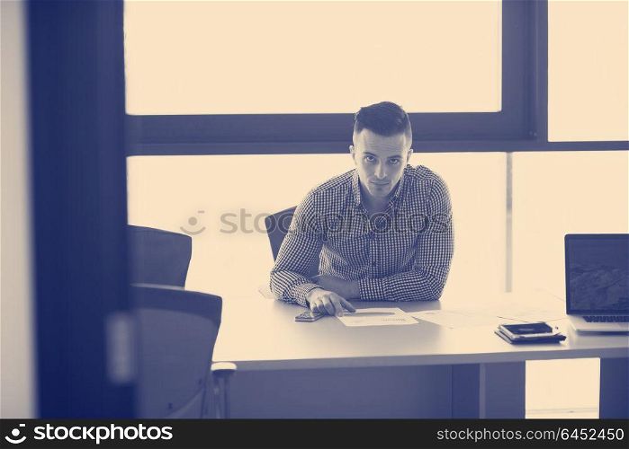 happy young businessman at his desk at work in modern startup business office interior