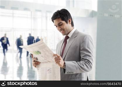 Happy young businessman in reading newspaper in office building