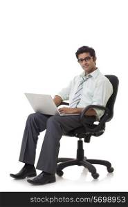 Happy young businessman on chair using laptop