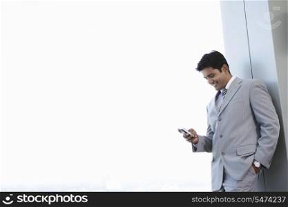 Happy young businessman reading text message on cell phone at office